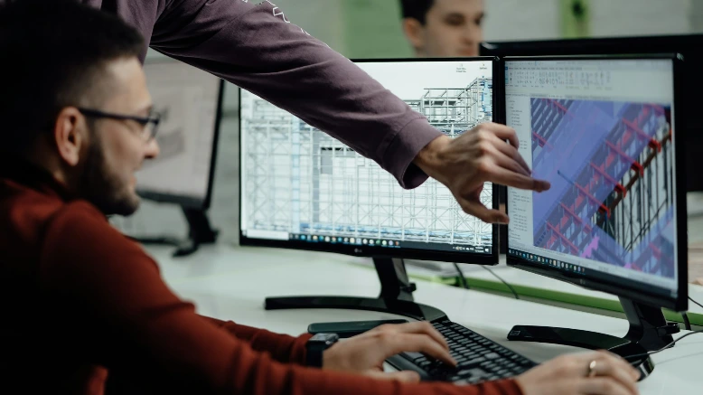 Colleagues collaborate while examining computer designs.